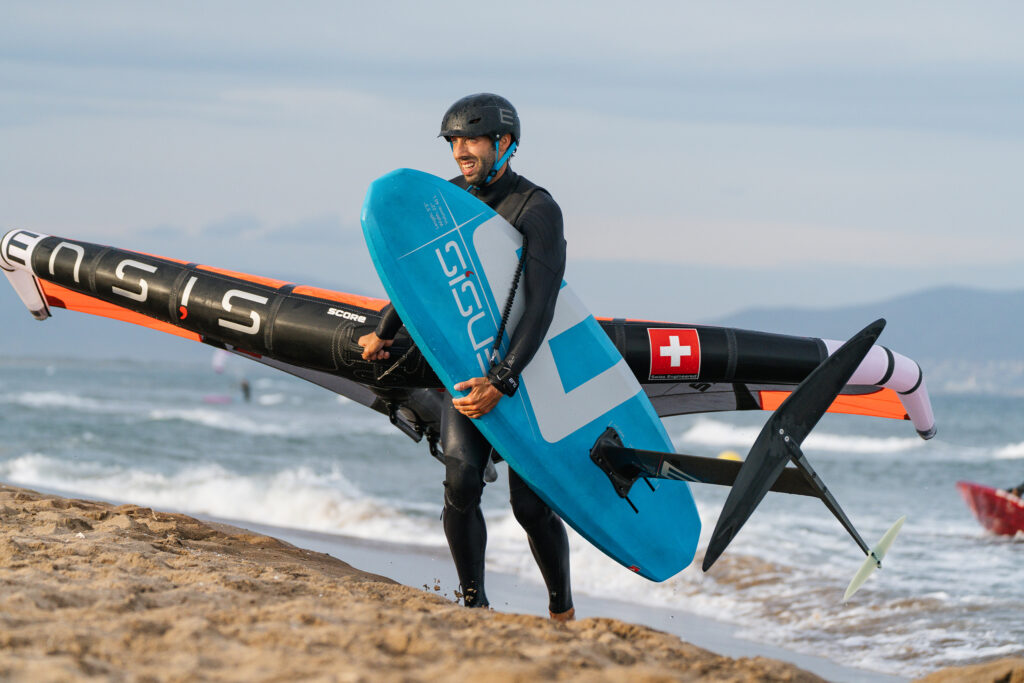 man carrying jive mid length board on beach
